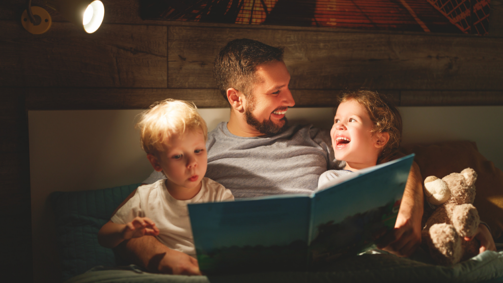 man reading a book for two kids